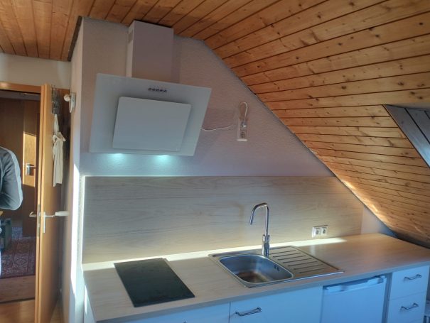 Küchenzeile unter Dachschräge mit Beleuchtung und Holzdecke