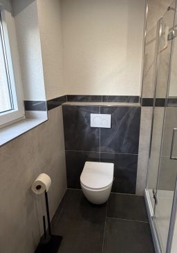 WC-Bereich im Bad WC-Bereich im modernisierten Bad mit dunklen Wandfliesen
